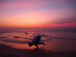 Magische Momente erleben Sie beim Yoga am langen Sandstrand während die untergehende Sonne alles um Sie herum in rosa Licht taucht