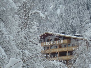 Das Naturhotel LechLife romantisch von schneebedeckten Bäumen umgeben