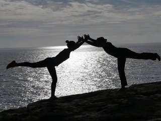 Herrliche Partner Yoga-Pose mit Blick aufs Meer
