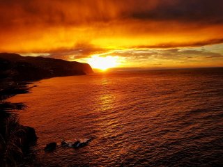 Meer, Steilküste, von Sonne feuerrot gefärbte Wolken - die Aussicht im Yoga Urlaub genießen