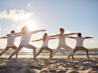 Üben Sie Yoga gemeinsam am Strand mit Gleichgesinnten