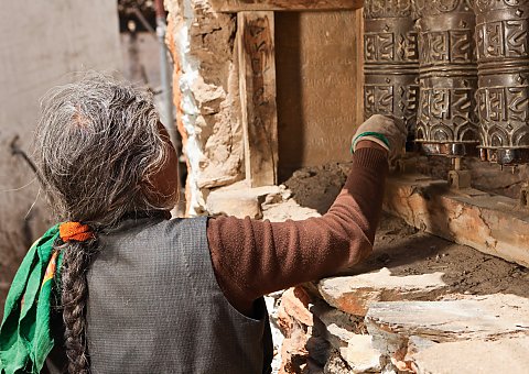 Eine Frau in Mustang dreht die Gebetsmühlen während Sie betet